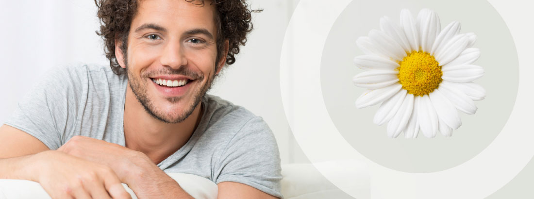 Portrait eines jungen, lächelnden Mannes mit Locken kombiniert mit einer großen Margerite. Die Blume ist Symbol des Praxis-Slogans: Schöne Zähne – schönes Leben.